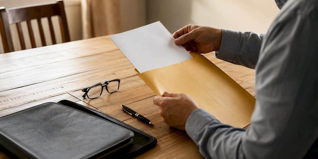 1787148364831_Hands-placing-legal-documents-into-envelope Hands placing legal documents into envelope